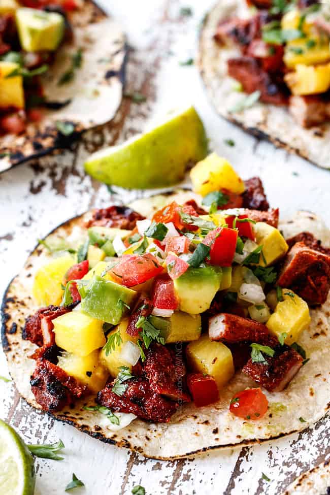 up close of authentic Al Pator with pineapple, pico de gallo and avocado on a white board