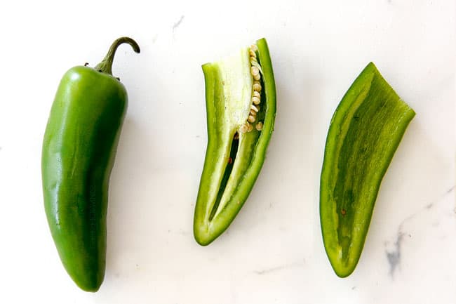 showing how to make pico de gallo by seeding and removing the ribs of jalapenos