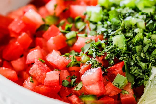 up close of tomatoes, cilantro, onions and jalapeno in a white bowl for authentic pico de gallo
