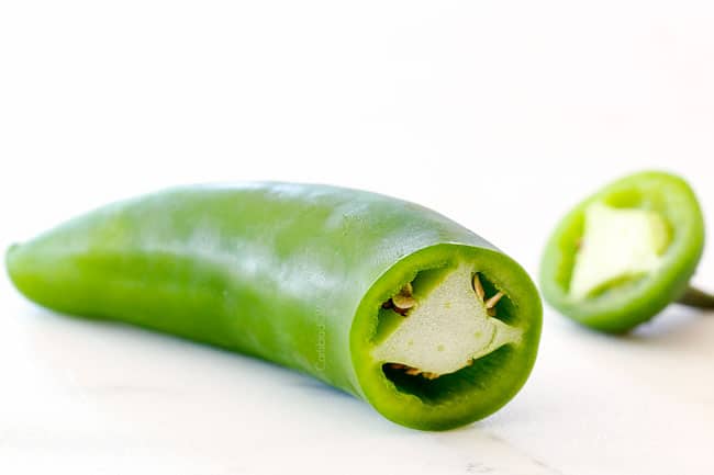 jalapeno on a white cutting board with the top chopped off showing how to make authentic pico de gallo