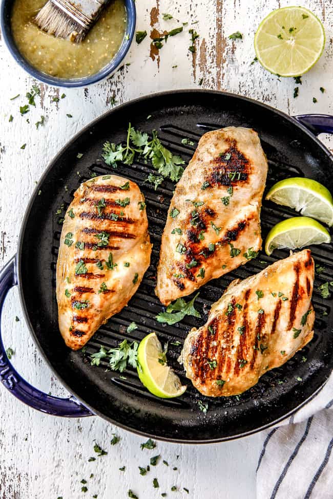 three pieces of Salsa Verde Chicken in a skillet with limes and cilantro