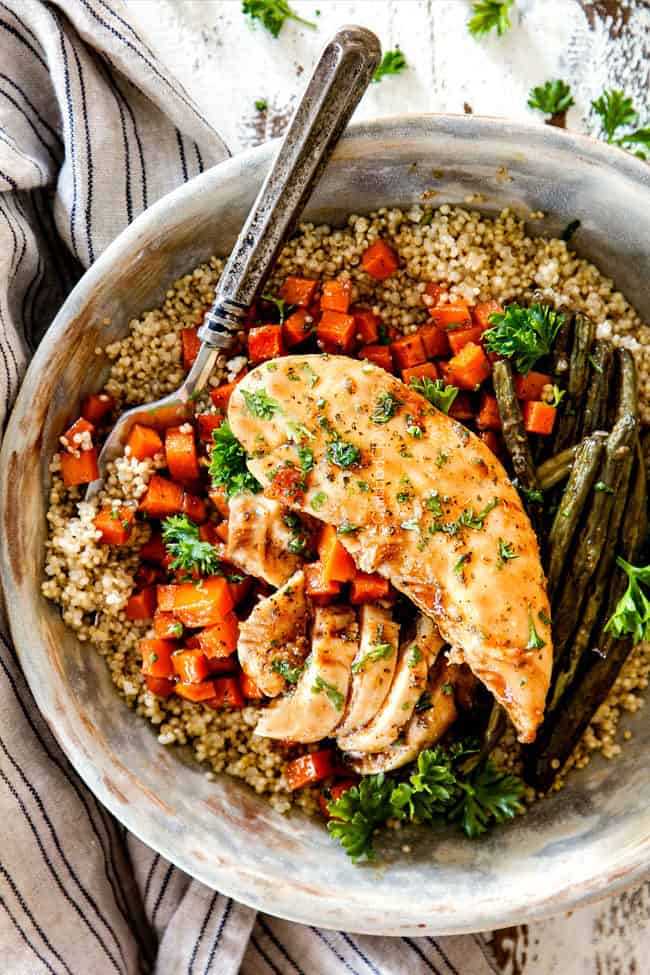 healthy sheet pan chicken and potatoes in a bowl with quinoa and a fork