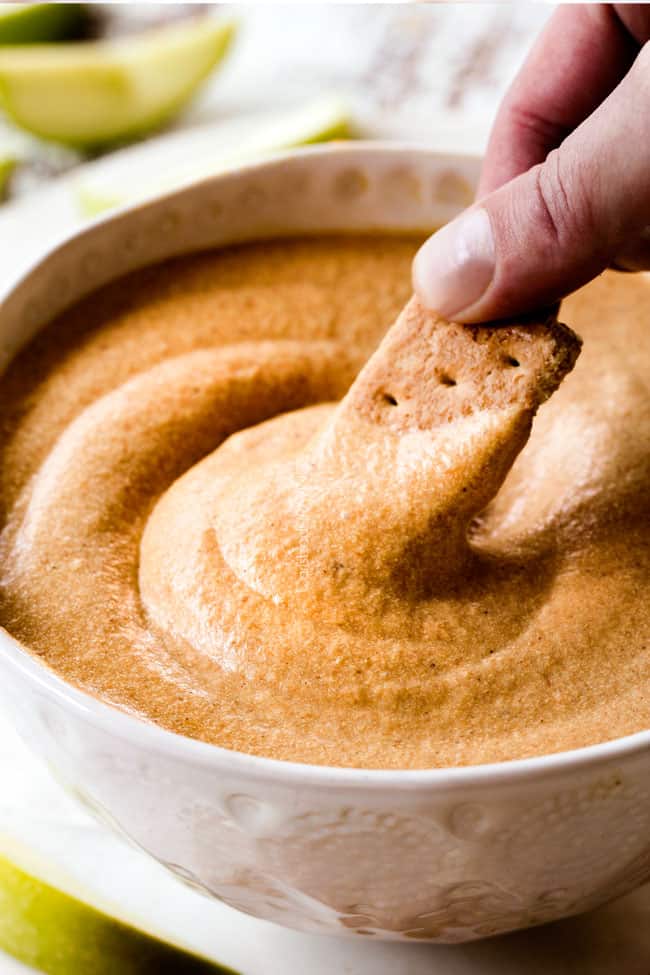 up close shot dipping a graham cracker into easy pumpkin dip