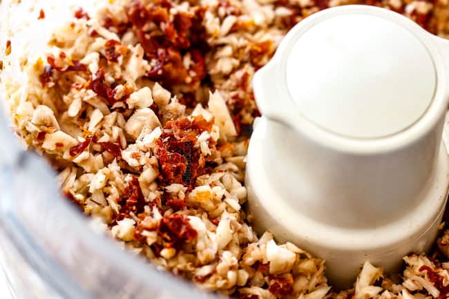 showing how to make sausage stuffed mushrooms by chopping mushrooms and sun-dried tomatoes in the food processor