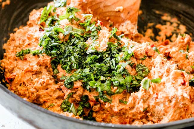 showing how to make easy sausage stuffed mushrooms by adding basil to sausage cream cheese filling