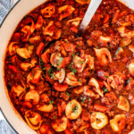 top view of a white Dutch oven of sausage tortellini soup