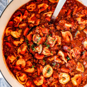 top view of a white Dutch oven of sausage tortellini soup