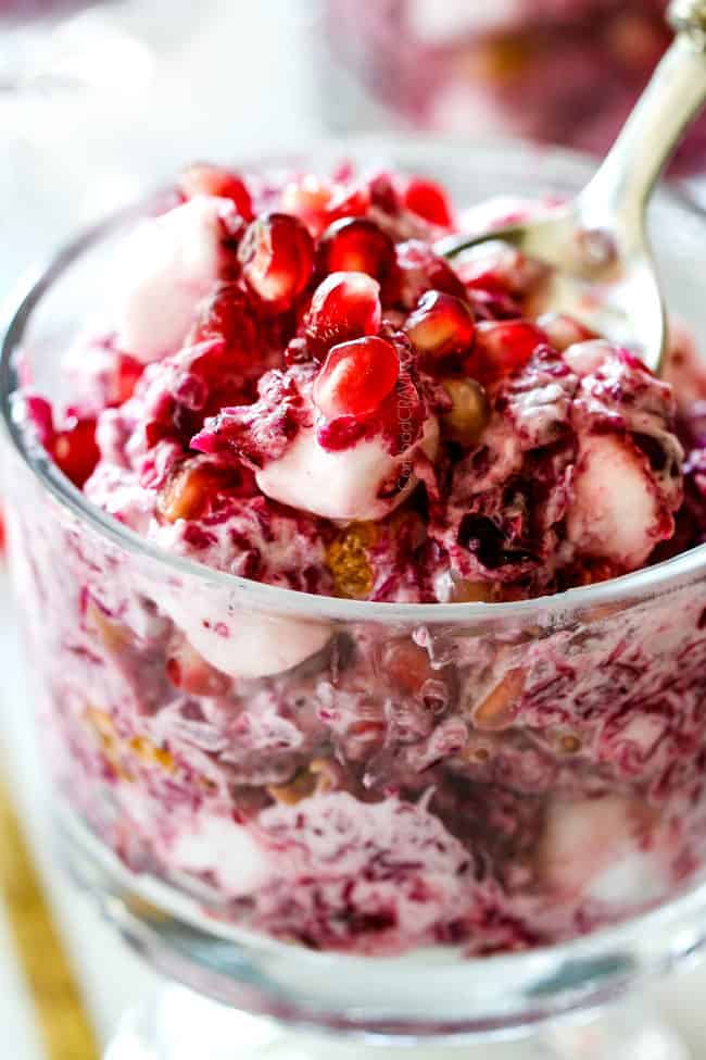 up close of creamy ambrosia salad in a small glass serving dish with pineapple, oranges, marshmallows