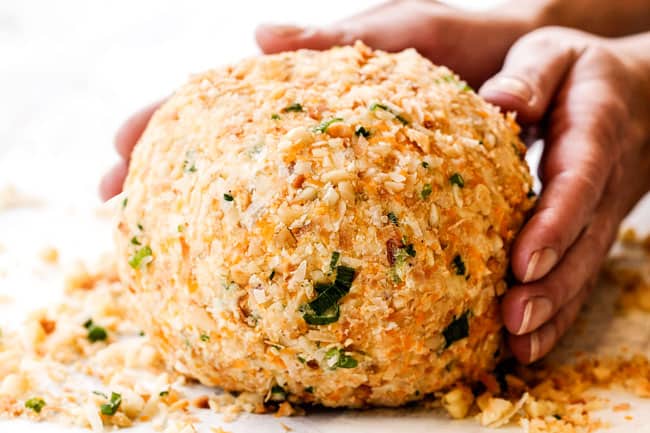 showing how to make Pineapple Cheese Ball by rolling in coating with macadamia nuts, coconut and green oninos