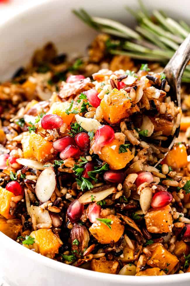 up close of seasoned wild rice recipe with a spoon raising rice out of the bowl