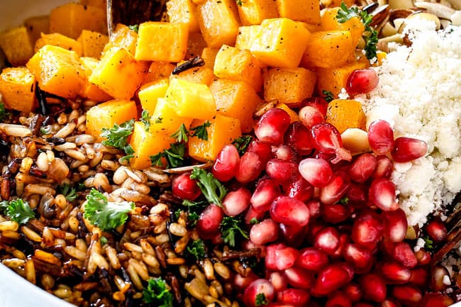 showing how to make best wild rice recipe by adding wild rice, squash, cranberries and feta to a white bowl