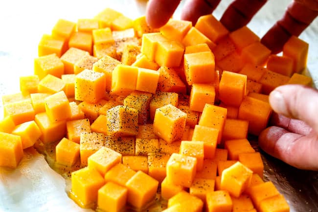 showing how to make healthy wild rice recipe by adding butternut squash, salt and pepper to a baking sheet o roast