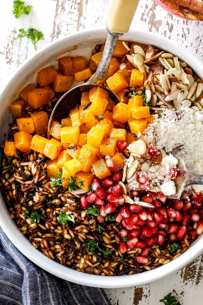showing how to make wild rice recipe side dish by adding wild rice, squash and pomegrantes to a white bowl