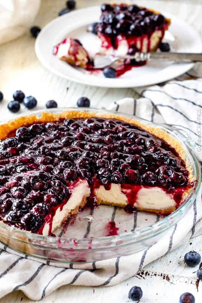 easy blueberry cheesecake recipe with fresh blueberries on a table with slices missing