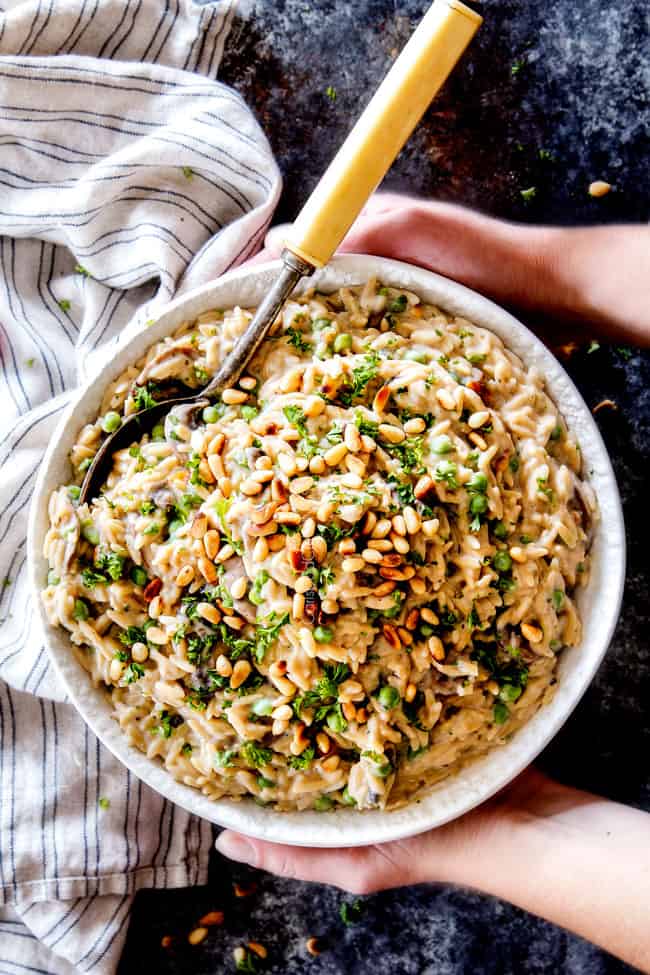 top view of holding cheesy orzo pasta in a white srving bowl
