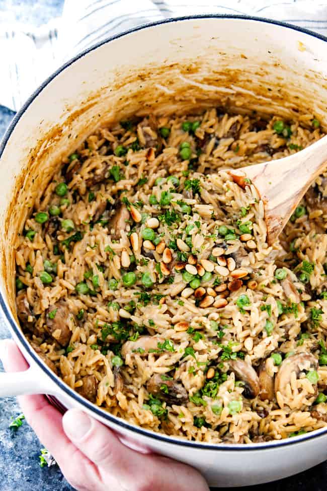 showing how to make orzo pasta recipe by stirring orzo pasta in a large Dutch oven