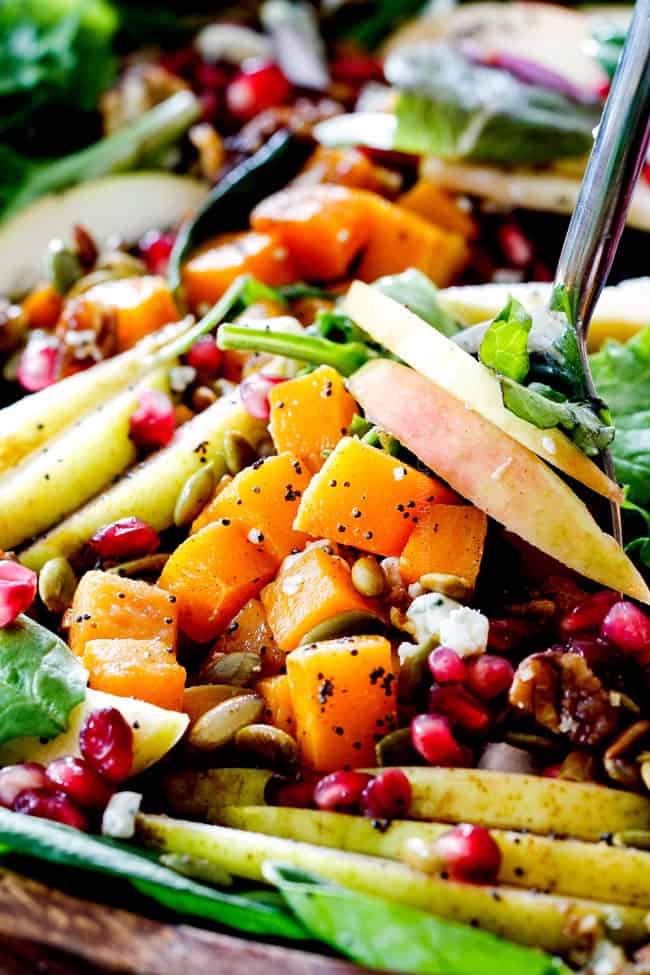 tossing Fall Salad with tongs that has pears and apples, pecans