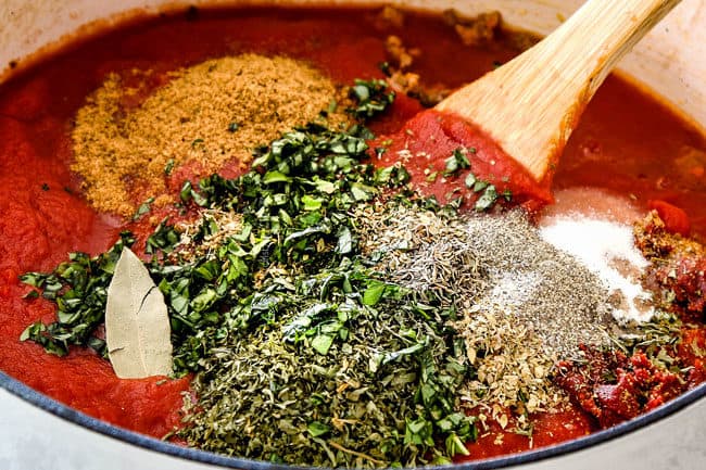 showing how to make traditional lasagna by making homemade Bolognese by adding tomato sauce, crushed tomatoes, tomato paste, fresh basil, parsley, and oregano to a pot