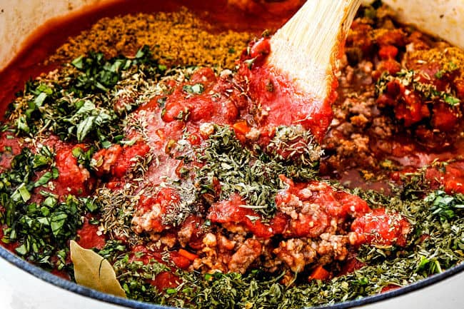 showing how to make best lasagna by making stirring homemade meat sauce with crushed tomatoes, tomato sauce, tomato paste, fresh basil, parsley, and oregano to a pot