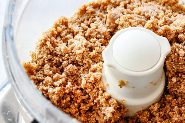 showing how to make pecan pie cheesecake with graham cracker crust by mixing graham crackers with butter and sugar in a food processor