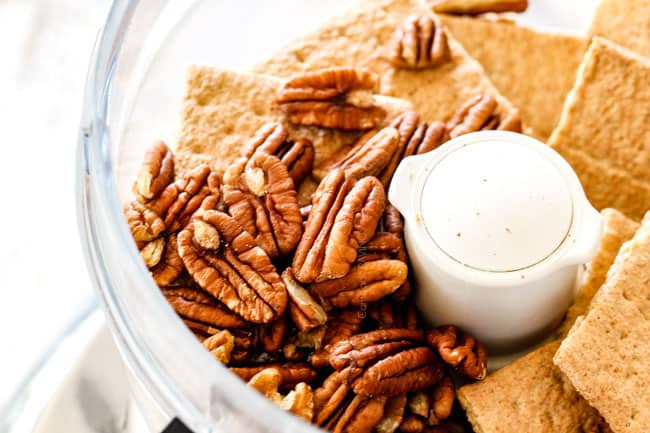 showing how to make pecan pie cheesecake by adding graham crackers for crust to food processor
