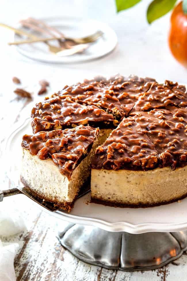 taking a slice of easy pecan pie cheesecake on a pedestal