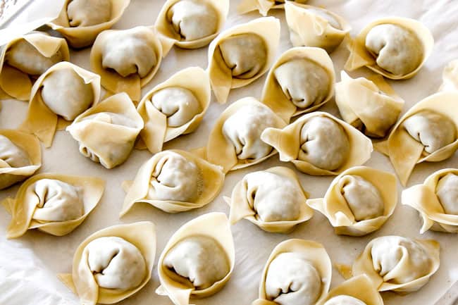 wrapped wontons on a baking sheet ready to go into authentic Wonton Soup
