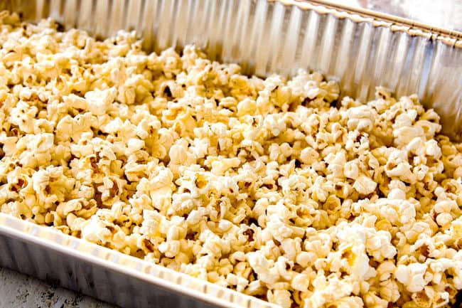 showing how to make caramel popcorn by adding popped popcorn to a large pan