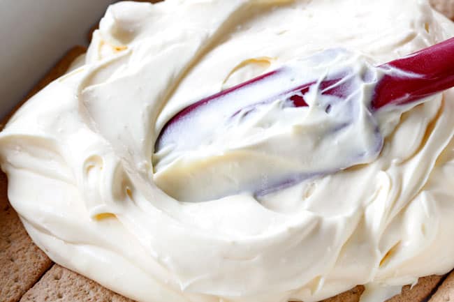 side view of showing how to make Chocolate Eclair Cake by spreading vanilla pudding and whipped cream over graham crackers