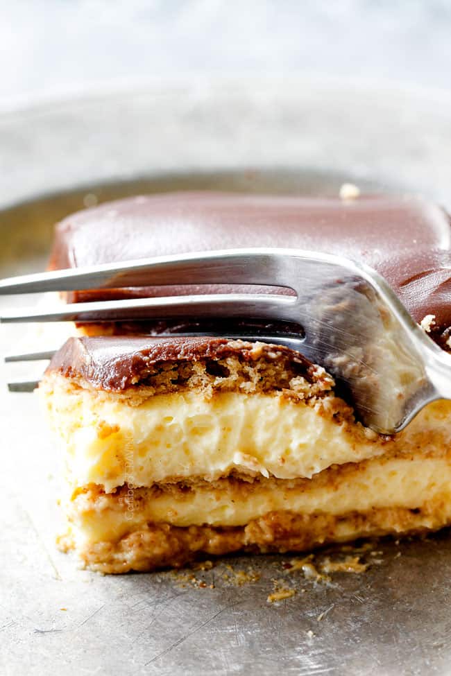 a fork taking a bite of side view of Chocolate Eclair Cake with chocolate frosting