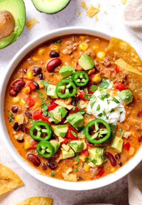 top view of taco soup recipe topped with chips, jalapenos, sour cream