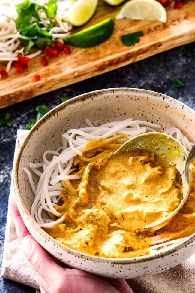 spooning best ever laksa recipe over rice noodles in a bowl