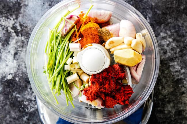 showing how to make Laksa paste for best ever laksaa recipe by adding ginger, lemongrass, shallots, garlic, turmeric, cumin, cilantro stems and red curry paste to food processor