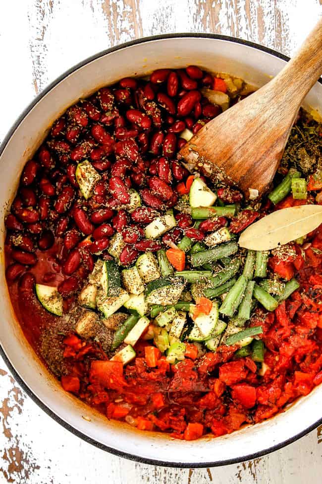 showing how to make Italian Minestrone Soup Recipe by adding green beans, zucchini, kidney beans, diced tomatoes to soup pot