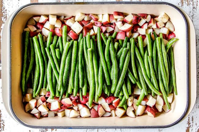 showing how to make Honey Mustard Chicken by layering red potatoes on the sides of the pan with green beans down the middle