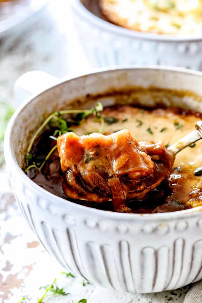 up close of a spoonful of traditional French Onion Soup holding a piece of Gruyere bread