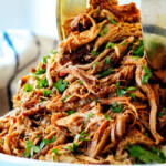 two tongs picking up some slow cooker pork for pork fajitas recipe