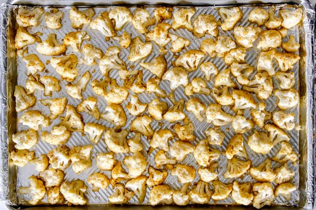 showing how to make roasted cauliflower by laying seasoned cauliflower in a single layer on a baking sheet