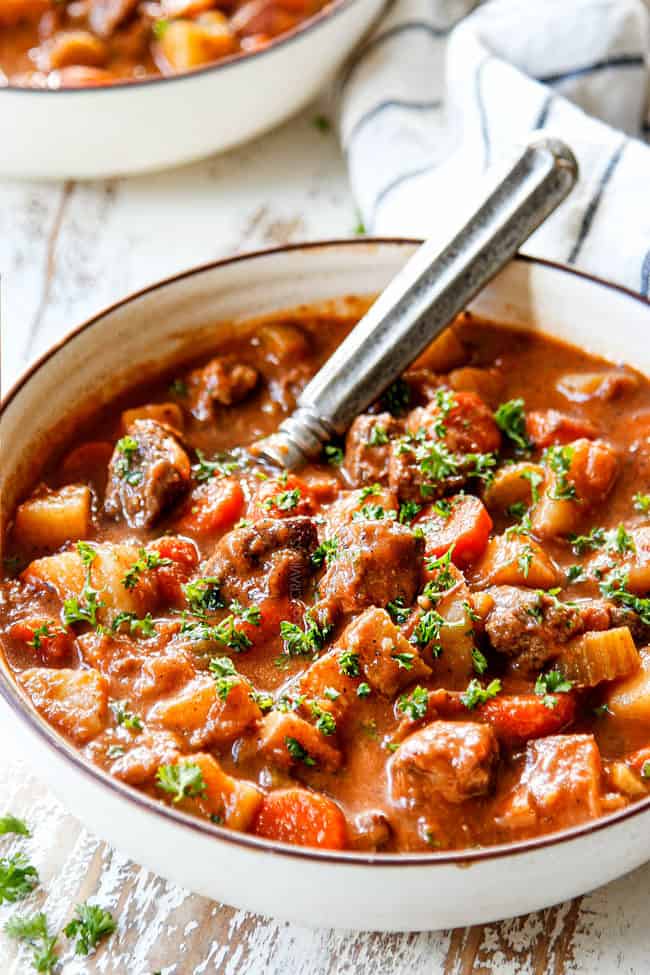crockpot beef stew with gravy in a bowl with potatoes, carrots, onions, celery and beef