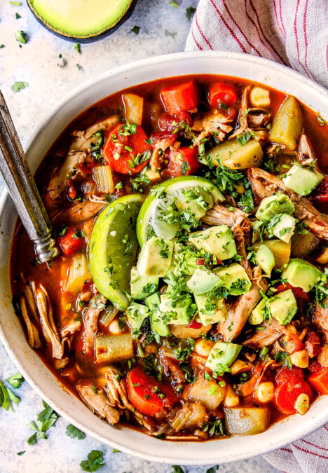 a bowl of authentic Caldo de pollo (Mexican Chicken Soup) toppd with avocadoes, cilantro and limes