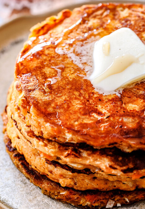 up close of sweet potato pancakes on a plate with syrup drizzled on top