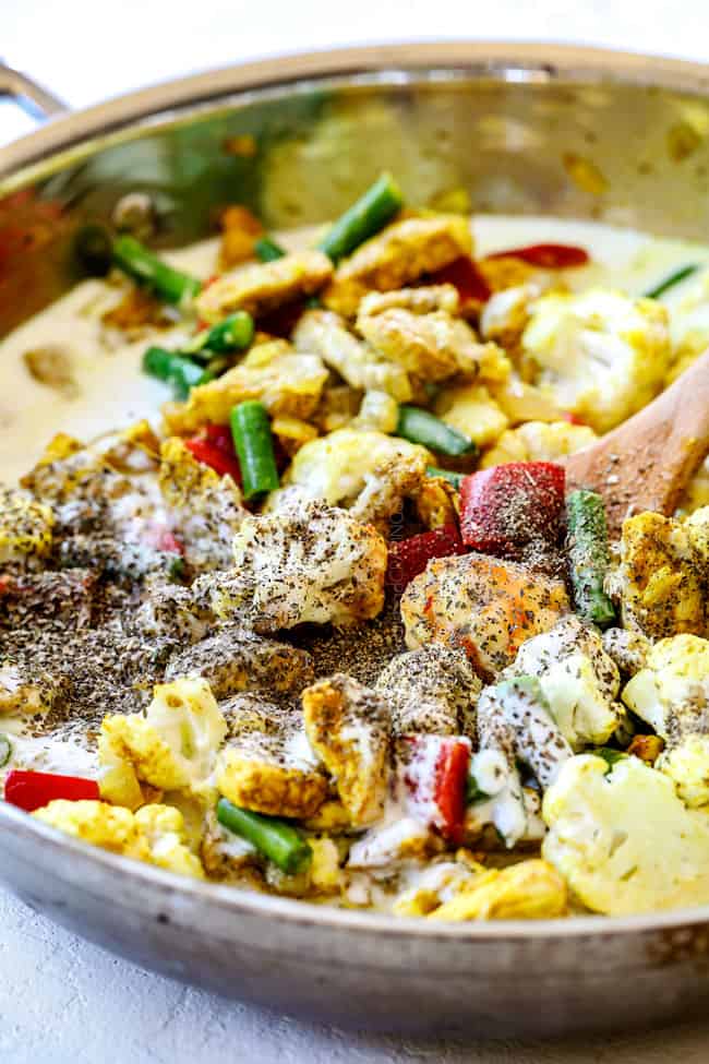 showing how to make thai coconut curry chicken recipe by adding coconut milk to a skillet with chicken and vegetables
