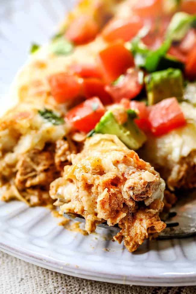 a serving of enchiladas verdes casserole on a white plate with a fork scooping up a bitee