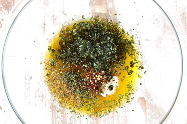 showing how to make lemon basil chicken by adding olive oil, basil, garlic, lemon juice and balsamic to a glass bowl