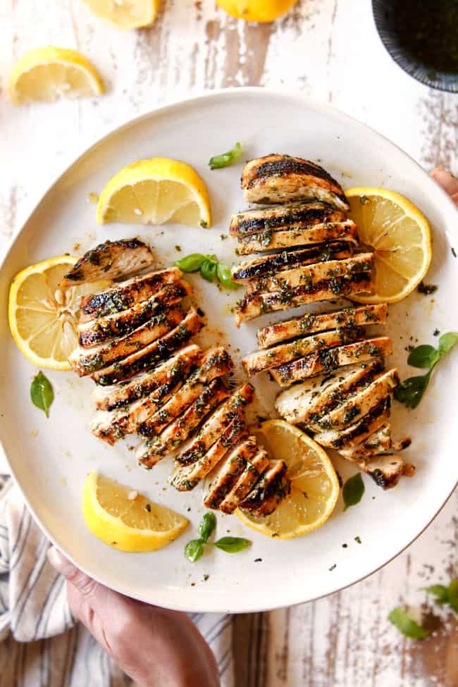 lemon basil chicken sliced on a white plate with lemon slices and basil