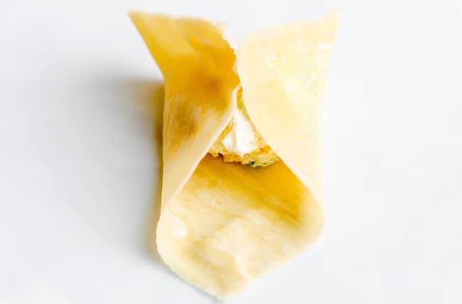 showing how to make cream cheese wontons by bringing up edges of wrappers