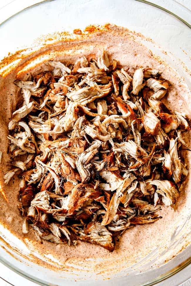 showing how to make chicken enchiladas by adding chicken to sour cream and enchilada sasuce