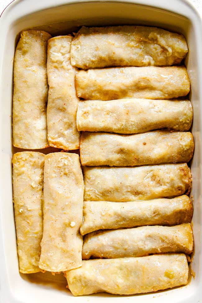 showing how to make chicken enchiladas by placing stuffed corn tortillas in a baking dish