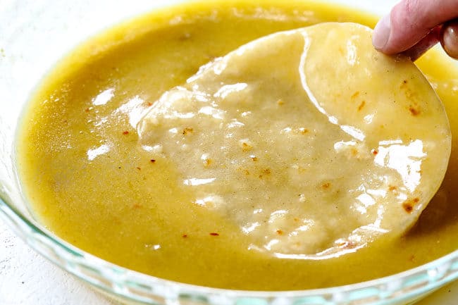 showing how to make enchiladas verdes by dipping corn tortillas in enchilada sauce