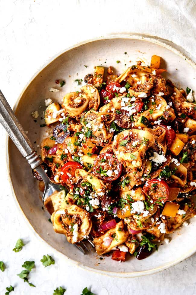 top view of Greek Pasta Salad recipe on a plate with olives, tomatoes, bell peppers, cucumbers, feta